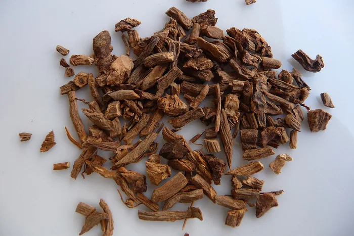 Pile of dried valerian root, coarse brown chopped pieces, on a plain white surface